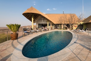 Una piscina al aire libre, sillones reclinables de piscina