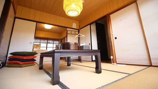 A traditional Japanese room with tatami flooring, a low wooden table, and a hanging lamp. - (Guest House) Kiyomori no Baika (Shimogyo Ward)