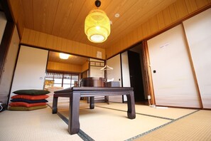 A traditional Japanese room with tatami flooring, a low wooden table, and a hanging lamp. - (Guest House) Kiyomori no Baika (Shimogyo Ward)