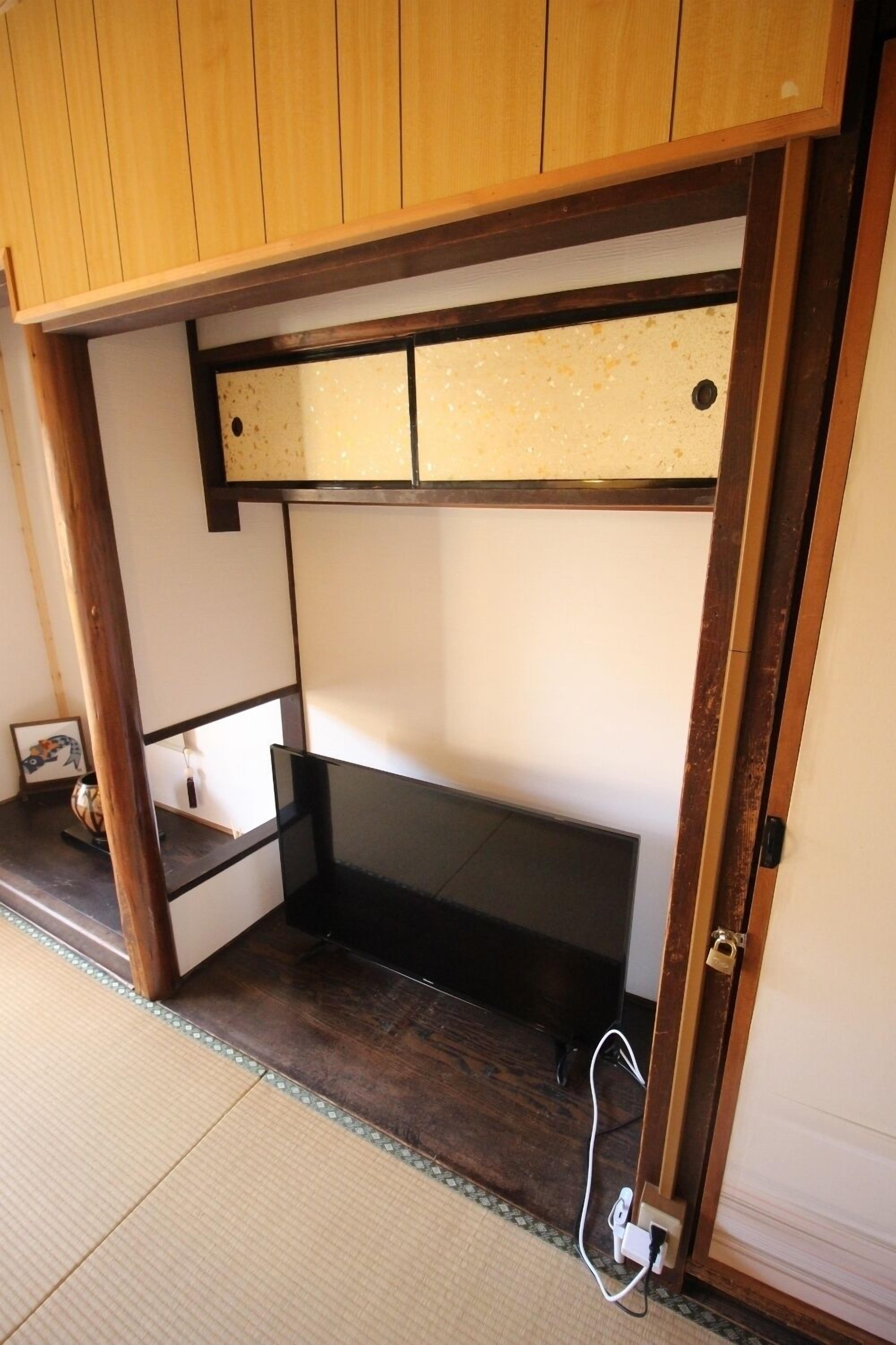 A room with a wooden ceiling, a black bench, and a small shelf with a picture frame.
