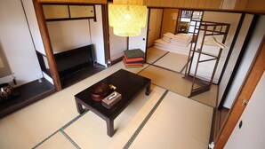 A traditional Japanese room with tatami flooring, a low wooden table, a television, and a hanging lamp. - (Guest House) Kiyomori no Baika (Shimogyo Ward)