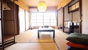 A traditional Japanese room with tatami flooring, a low table, and a hanging light fixture. - (Guest House) Kiyomori no Baika (Shimogyo Ward)