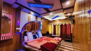 Un dormitorio moderno con cabecera de madera, una cama grande con colcha floral roja, una mesita de noche y un aplique de techo.