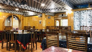 Un restaurante con paredes y techo de madera, mesas con manteles rojo y negro, y un cartel de 'No Smoking'.