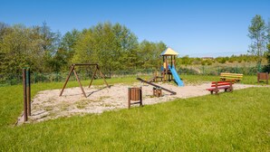 A playground with swings, a slide, and a bench. - Apartamenty Sun & Snow Osiedle Wybrzeże (Ustronie Morskie)