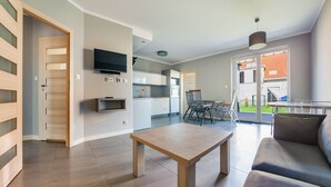 A modern apartment with a dining area, kitchen, and living room. - Apartamenty Sun & Snow Osiedle Wybrzeże (Ustronie Morskie)