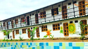 Un edificio de dos pisos con una piscina de azulejos al frente.