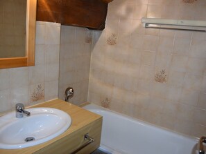 Ein Badezimmer mit Waschbecken, Holzschrank und einer Badewanne.