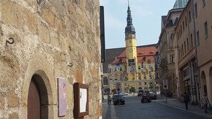 A cobblestone street with historic stone buildings, a prominent yellow tower, and a clear sky. - Pension & Restaurant Zum Echten (Bautzen)