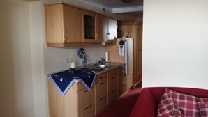 A compact kitchen with wooden cabinets, a sink, and a refrigerator. - Pension & Restaurant Zum Echten (Bautzen)