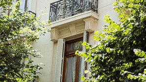 Un edificio de varios pisos con balcones, ventanas grandes y barandillas de hierro decorativo.