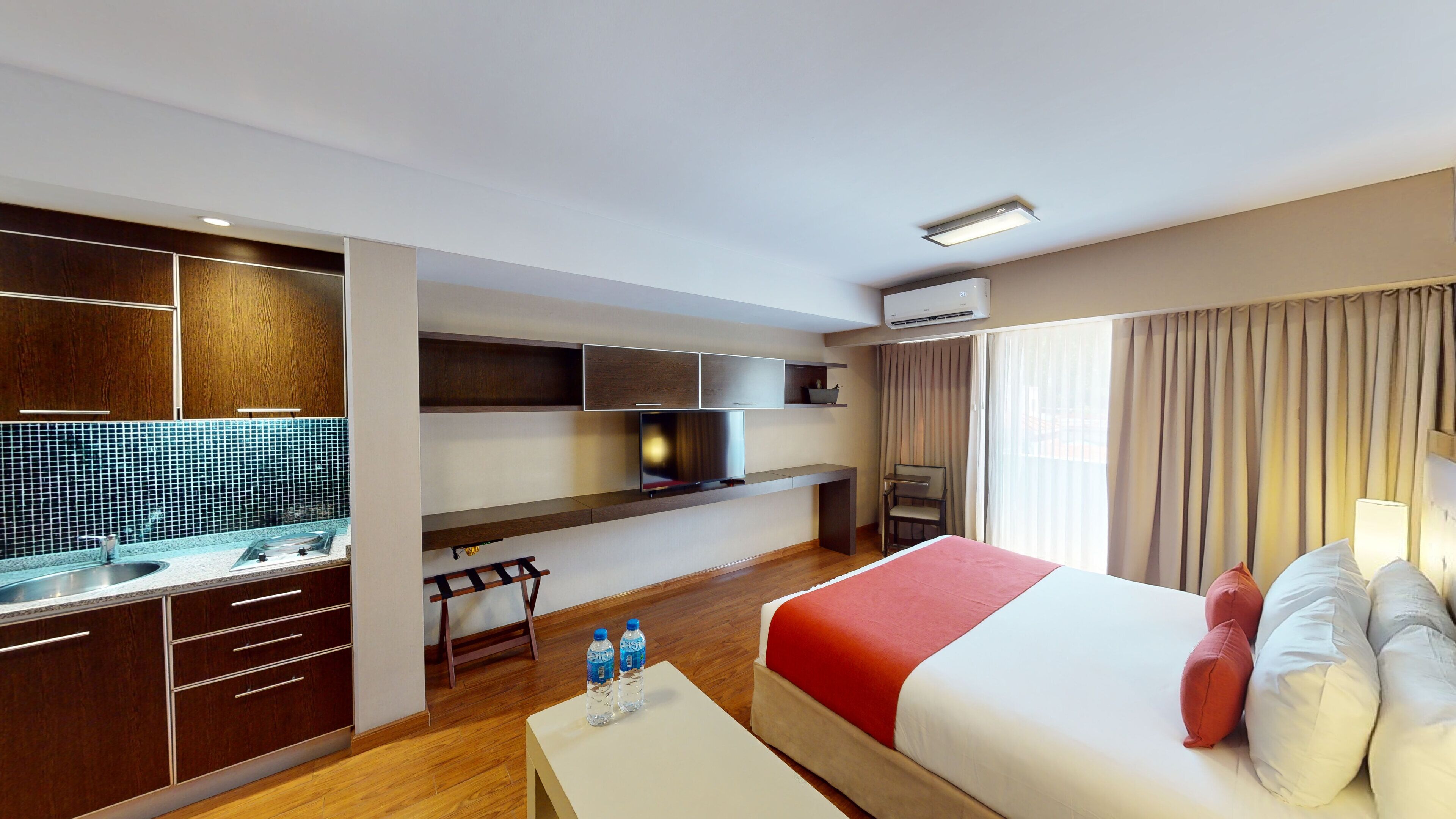 Hotelkamer met een bed, bureau met televisie, minibar en een badkamer met douche.