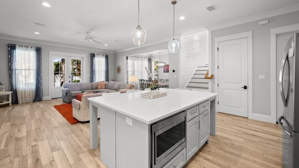 Una cocina moderna con una isla central, muebles blancos y electrodomésticos de acero inoxidable.