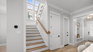 Una escalera de madera con barandilla, que lleva a una puerta blanca.