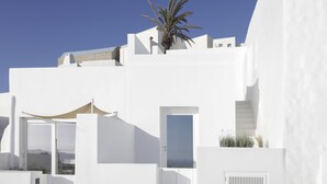 Un bâtiment blanc avec un palmier, une porte et un escalier.