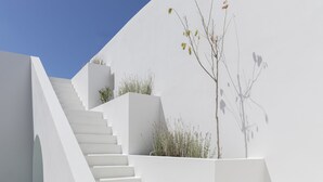Un escalier blanc montant le long d’une pente, entouré de murs blancs et surplombant un ciel bleu clair.