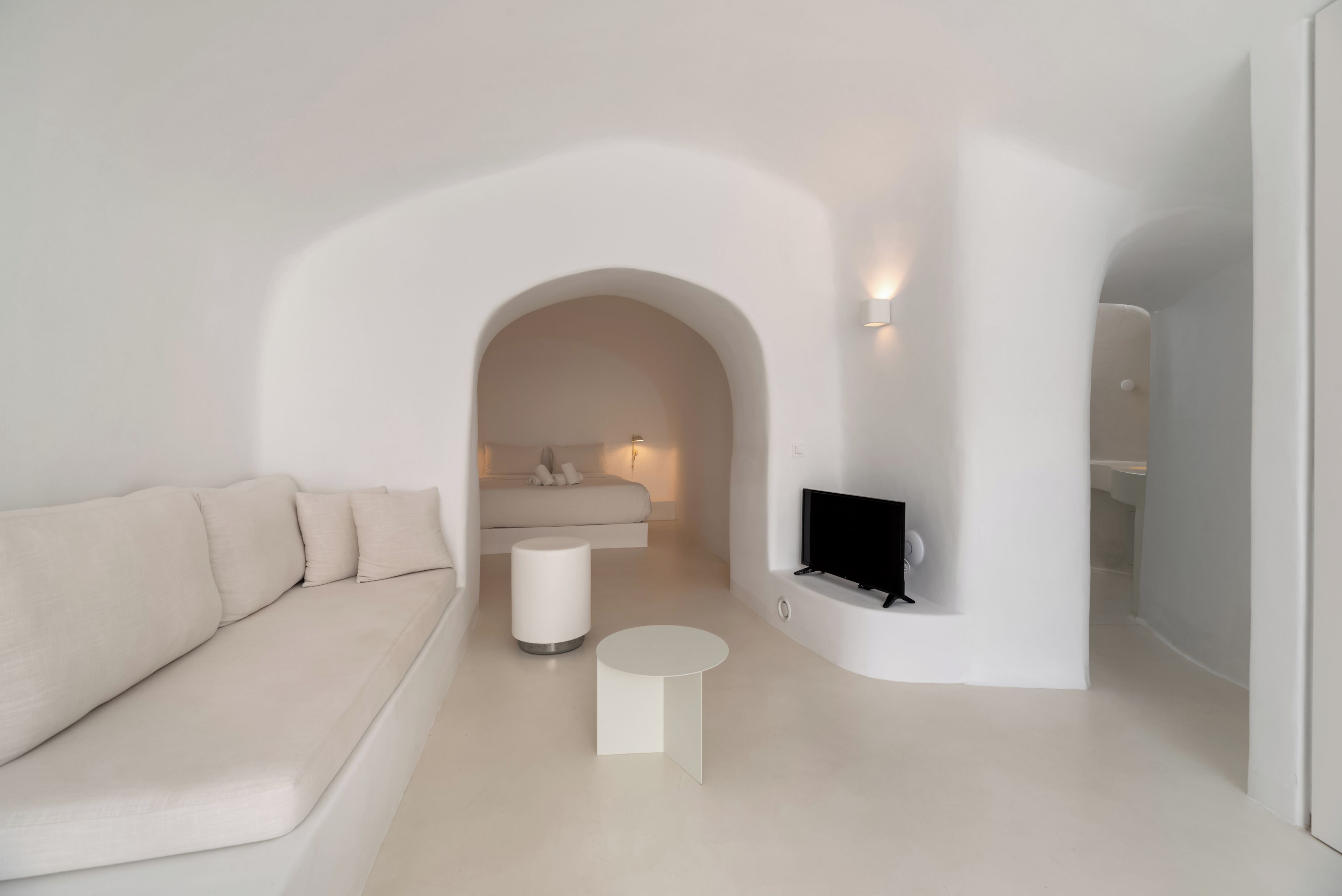 Un salon moderne et minimaliste, avec un canapé, une petite table ronde et un téléviseur fixé au mur.