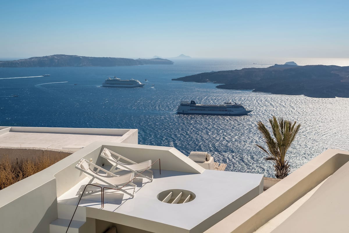 Un hôtel moderne doté d’une terrasse sur le toit offrant une vue sur une mer calme, ainsi que d’une piscine et d’un palmier.