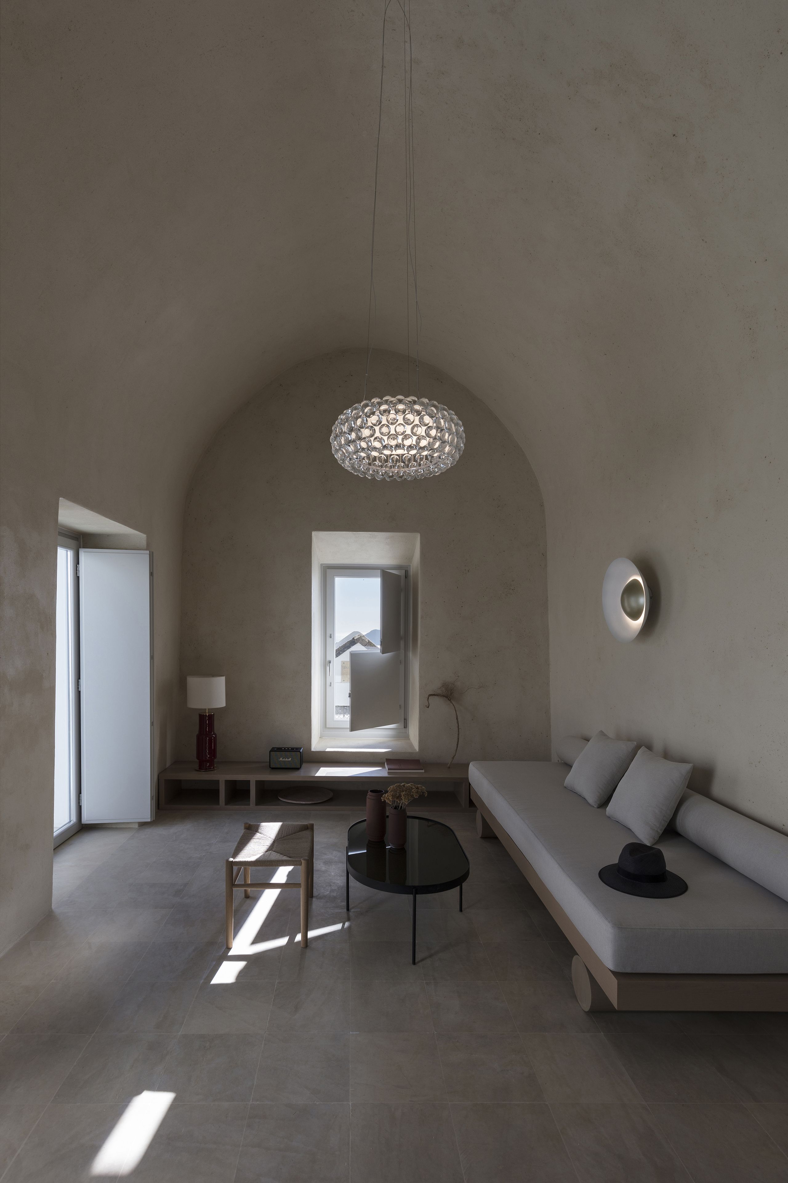 Una sala de estar moderna con un sofá, una mesa de centro y una lámpara. Se ve una ventana con vistas a una montaña.