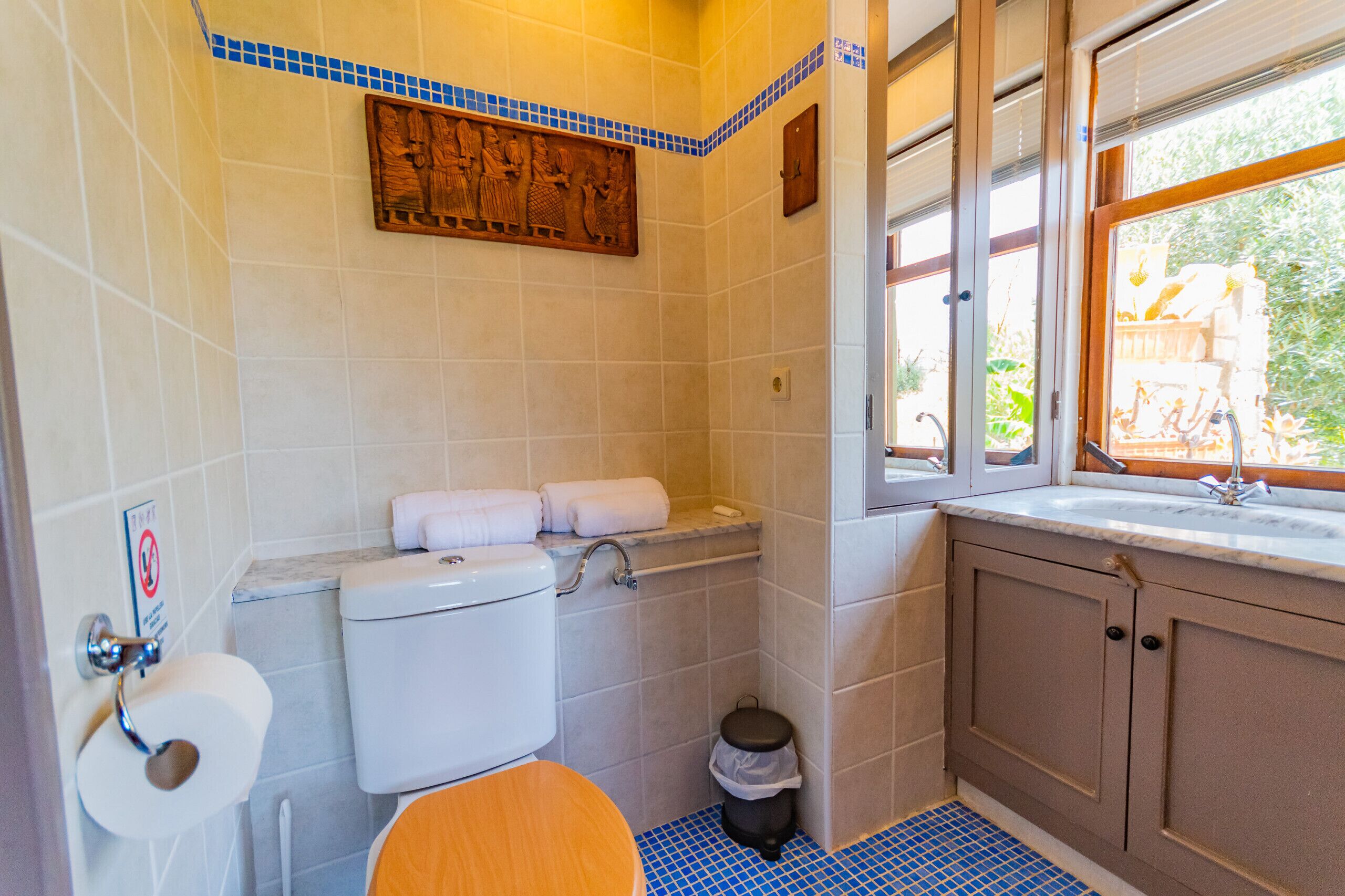 A bathroom with a toilet, sink, and window.