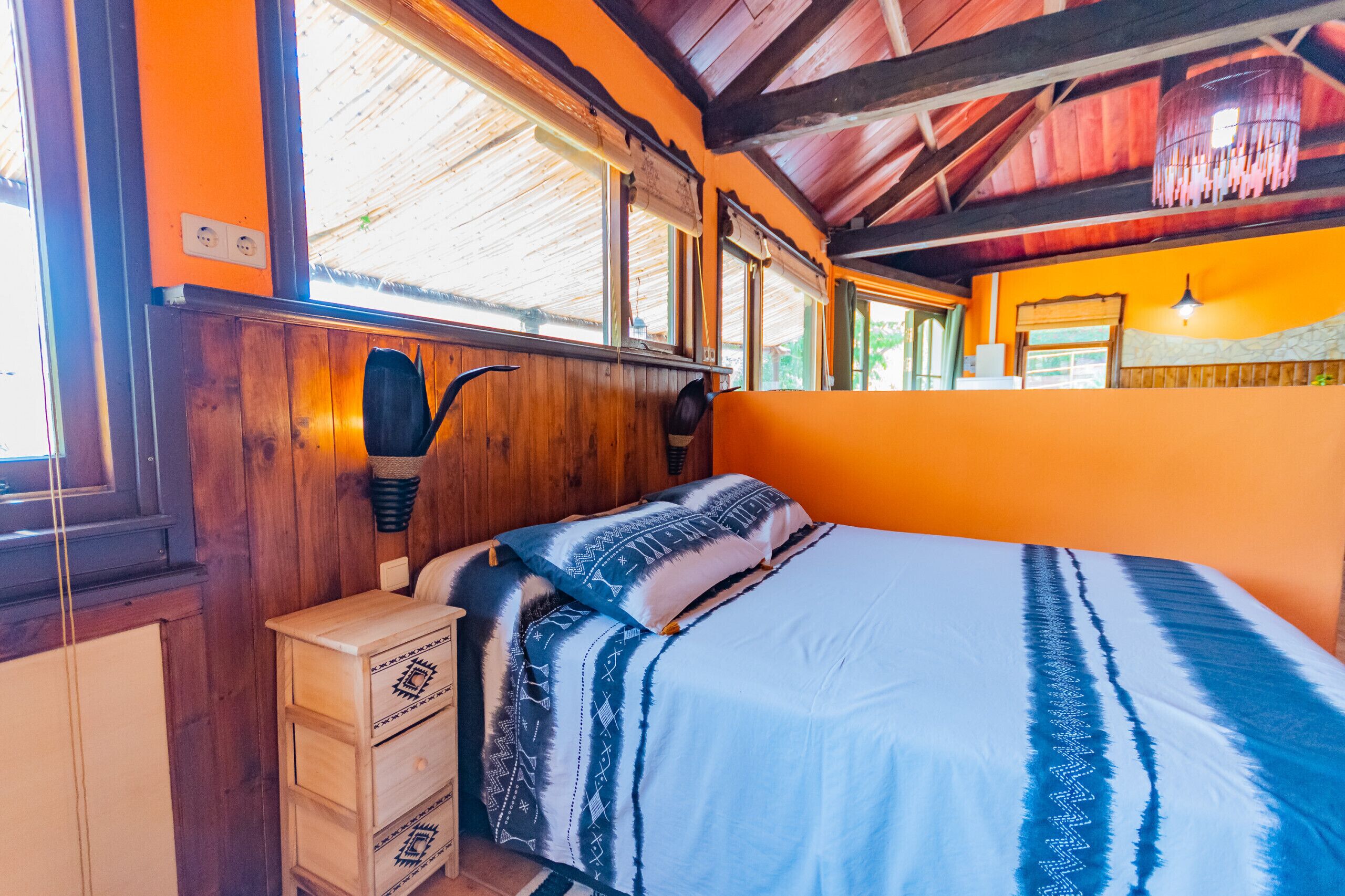 A room with a bed, wooden walls, a window, and a light fixture.