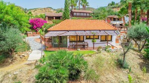 A Mediterranean-style villa with a tiled roof, surrounded by lush greenery and a stone pathway leading to the entrance. - Cubo's Mijas Finca Huerta Rica Sabana / shared pool / views (Mijas Pueblo)