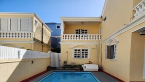 Una piscina rodeada por un edificio con balcón y una valla blanca.