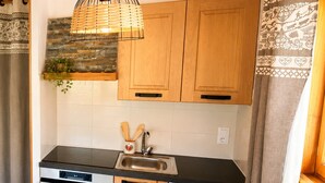 A kitchen with wooden cabinets, a stove, a sink, and a dining table with chairs.