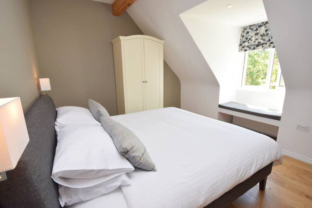 A bedroom with a bed, a wardrobe, a window with a view, and a lamp.