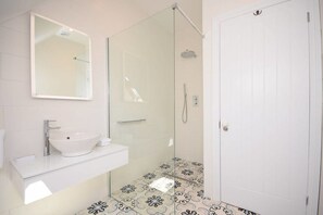 A modern bathroom with a glass-enclosed shower, a white sink, and a mirror above the sink.