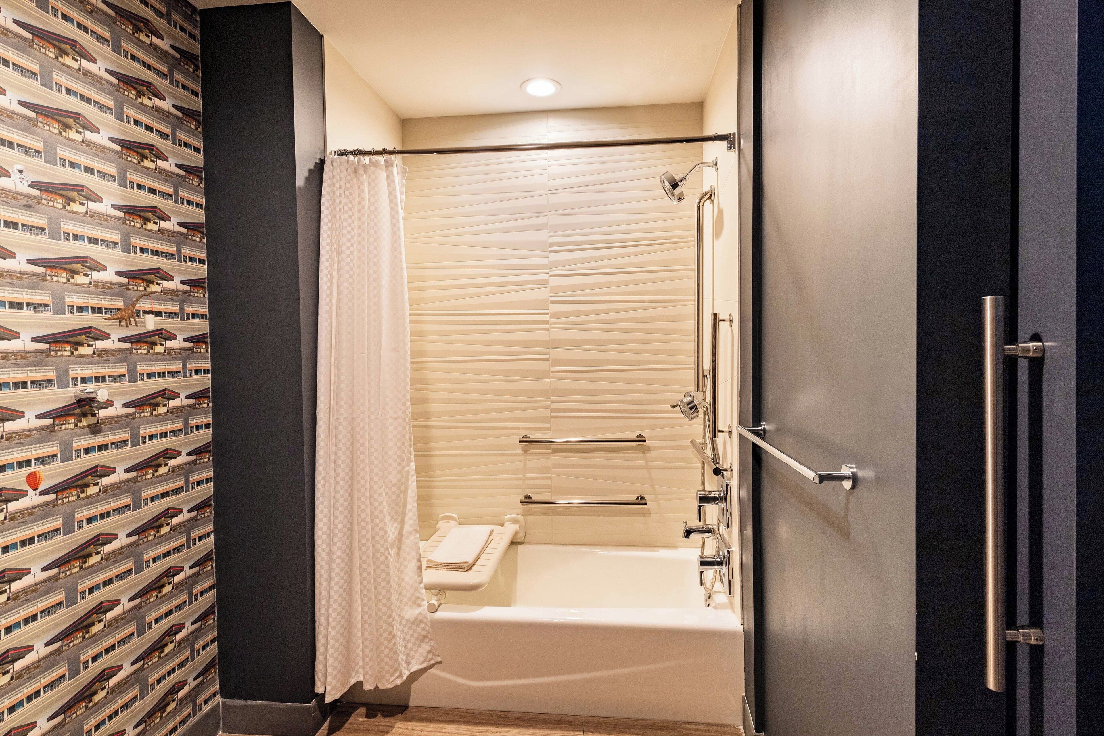 A modern bathroom with a bathtub, shower, and a towel rack.
