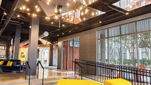 A modern lounge area with a sofa set, a small table, and a railing. - Aloft by Marriott Savannah Downtown Historic District (Savannah)