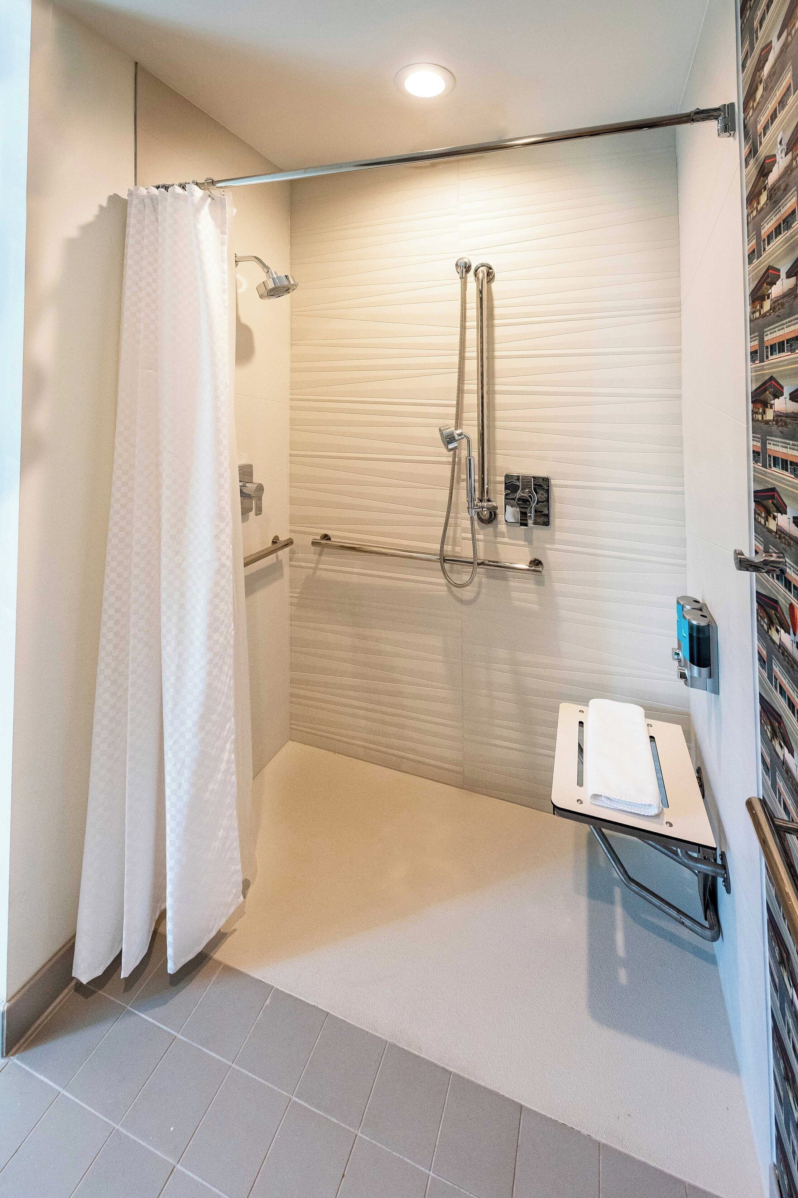 A modern bathroom with a glass shower enclosure, a towel rack, and a small shelf with toiletries.