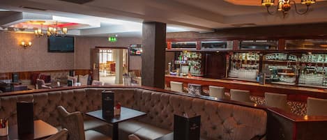 Een barruimte met zachte zitplaatsen en een bar die diverse flessen toont.
