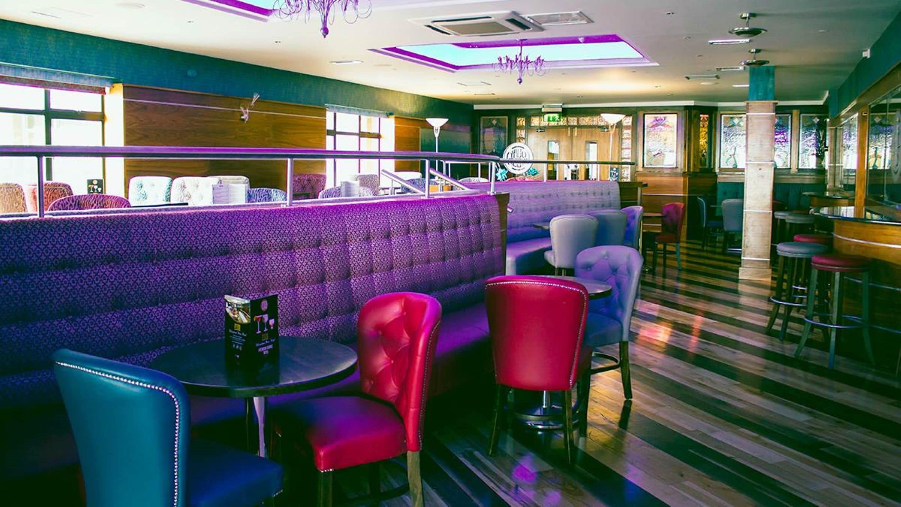 Un restaurante con una zona de estar de color morado, que incluye un banco acolchado y varias sillas.