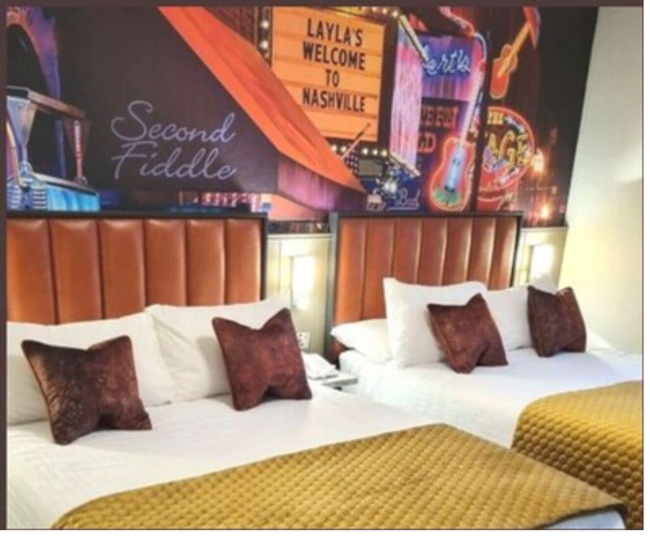 A hotel room with two beds, a sign reading "Layla's Welcome to Nashville," and a neon sign in the background.