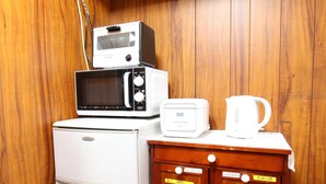 A compact kitchenette with a white refrigerator, microwave, toaster, and coffee maker on a wooden cabinet. - Osaka 2 story-house, Namba 10mins by bus (Ōsaka-shi)