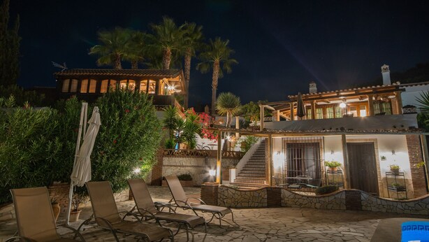 A well-lit outdoor patio area with lounge chairs, a staircase leading to a second level, and a view of the night sky.