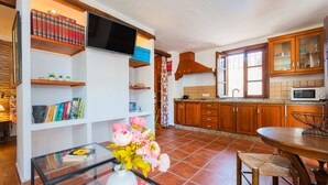 A kitchen with wooden cabinets, a tiled backsplash, and a dining area with a table and chairs.