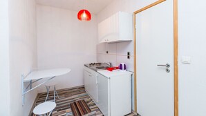 Pieni, käytännöllinen keittiö, jossa on valkoinen työtaso, pieni pesuallas ja pienikokoinen jääkaappi.