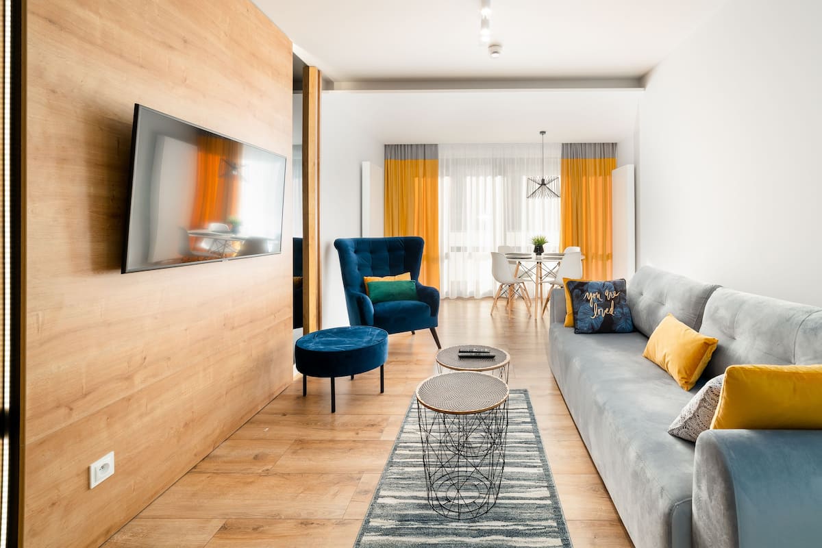 Una sala de estar moderna con un sofá gris, un sillón azul y una mesa de centro redonda.