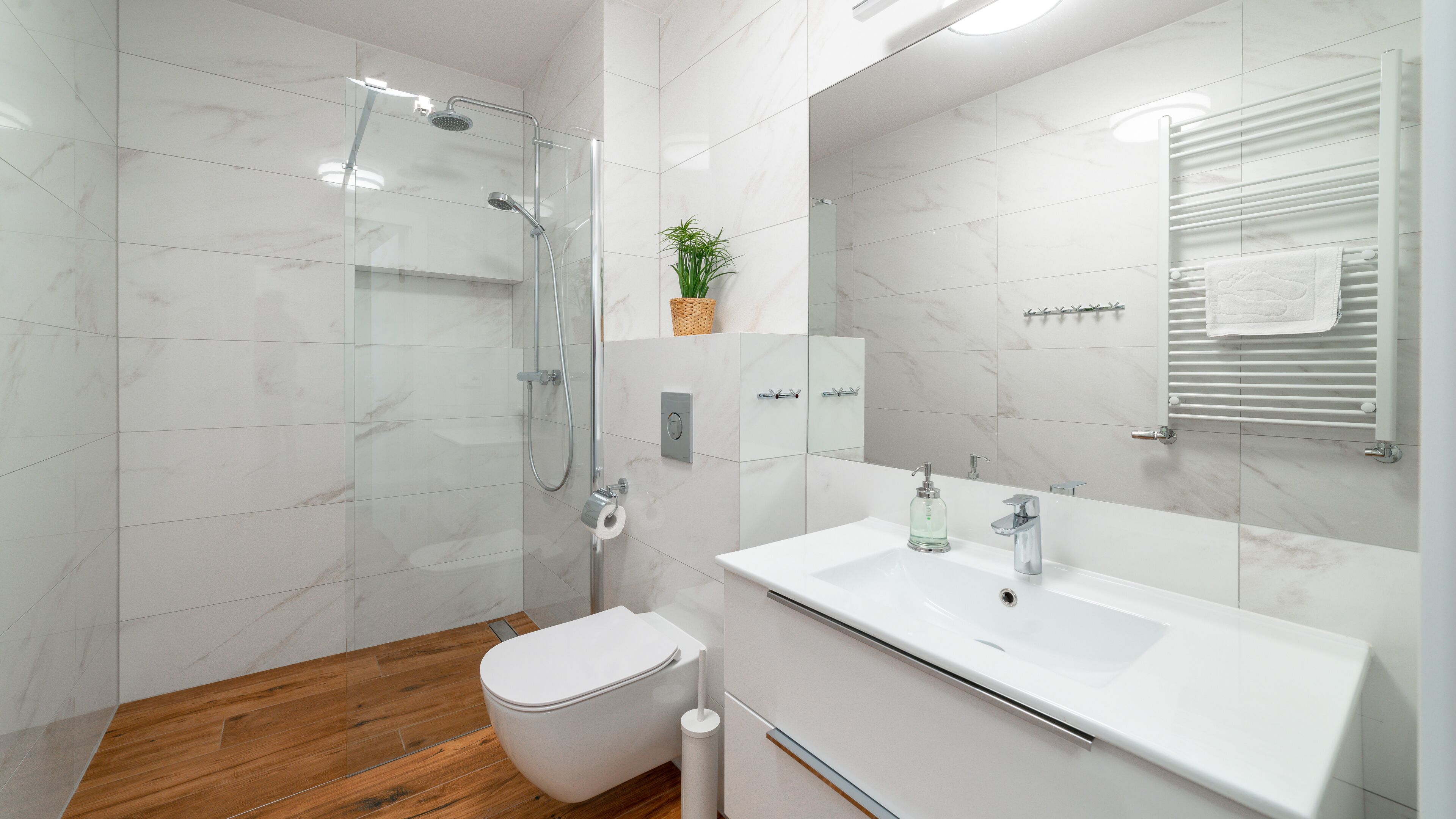 A modern bathroom with a shower, toilet, and sink.