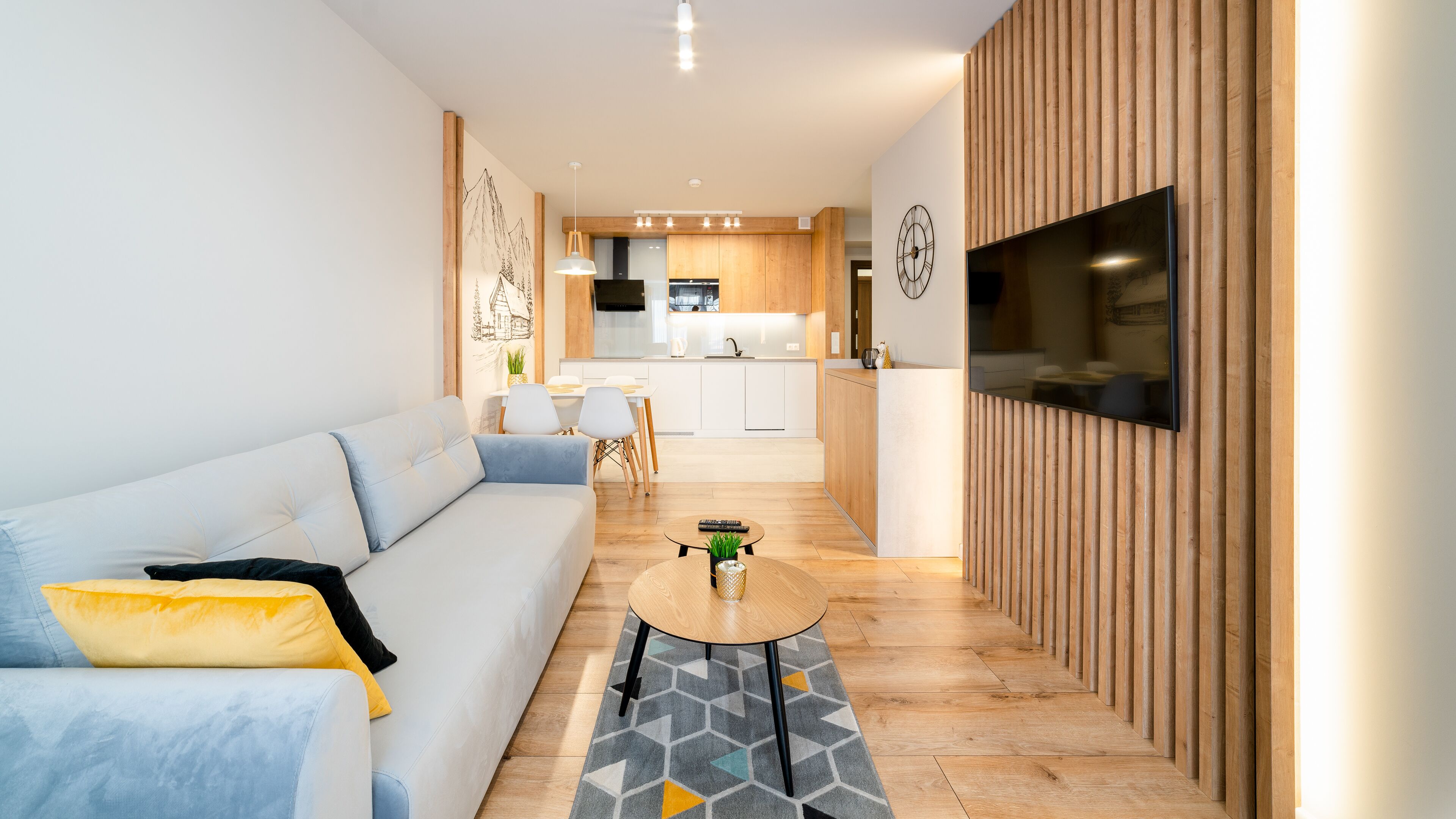 Una sala de estar moderna con un sofá, una mesa de centro y un televisor montado en una pared de madera.