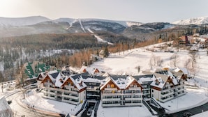 A modern lodge with a central courtyard, multiple guest rooms, and a ski slope in the background. - Sun & Snow Triventi Mountain Residence (Karpacz)