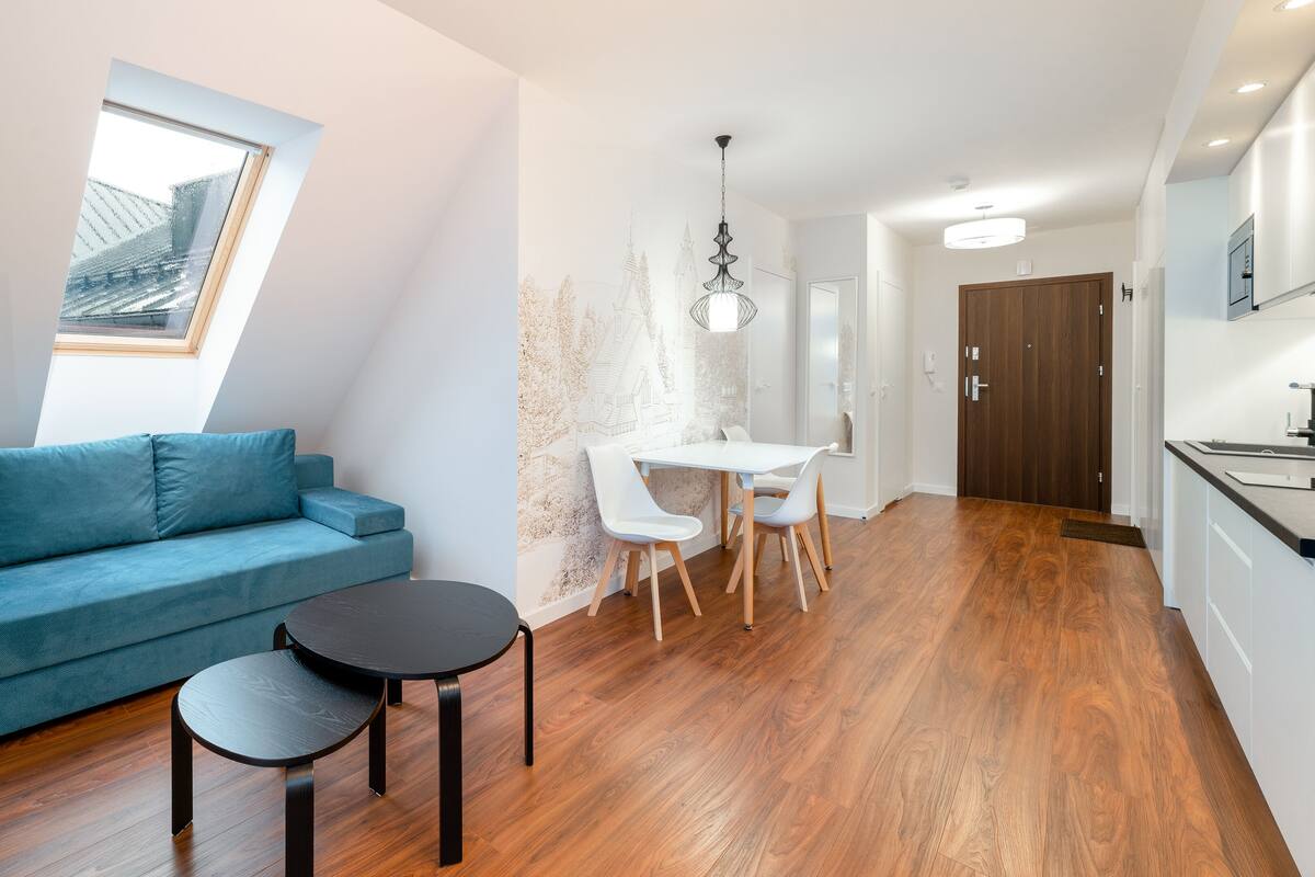 Una sala moderna con un sofá azul, una mesita redonda y una lámpara.