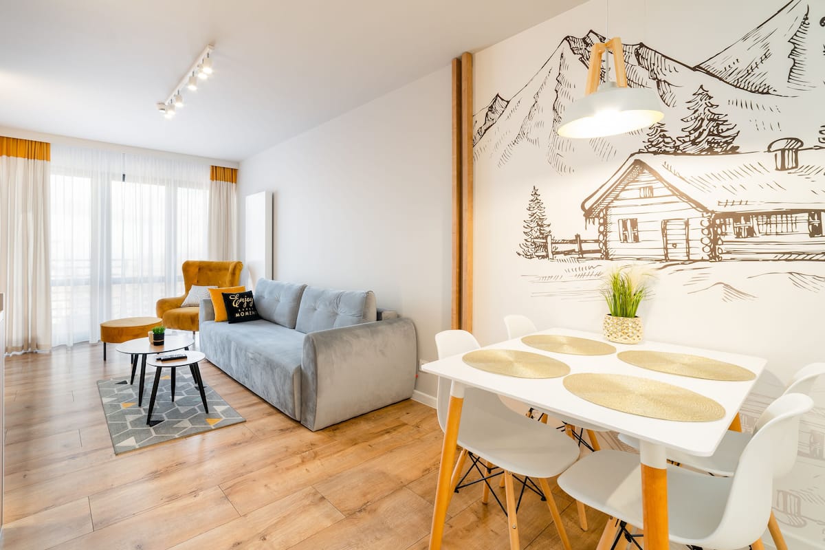 Una sala de estar moderna con un sofá, una mesa de comedor con sillas y una zona de cocina.