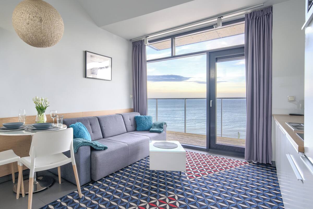 Una habitación de hotel moderna con balcón, comedor y cocina.