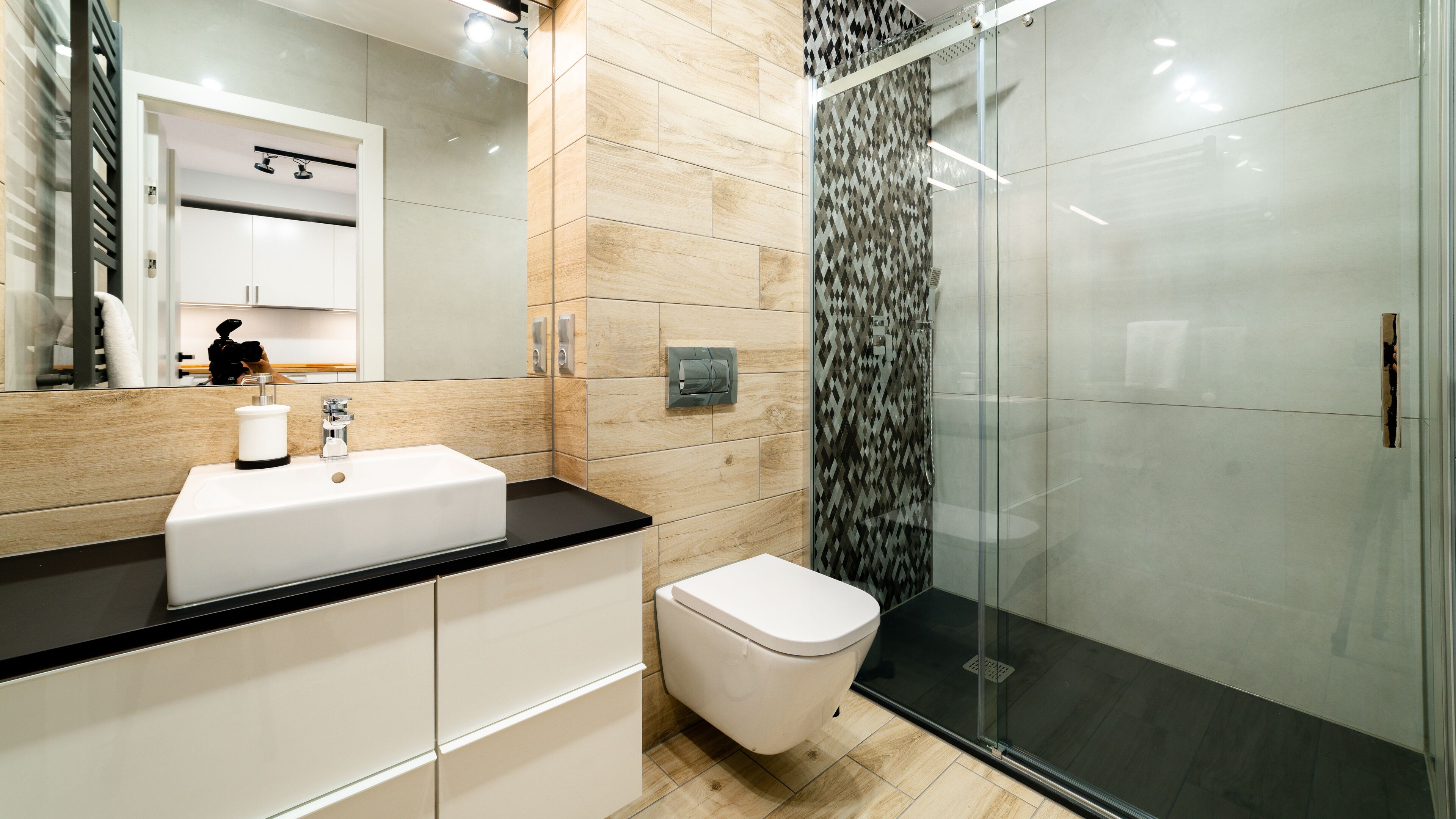 A modern bathroom with a white sink, a toilet, and a glass shower enclosure.