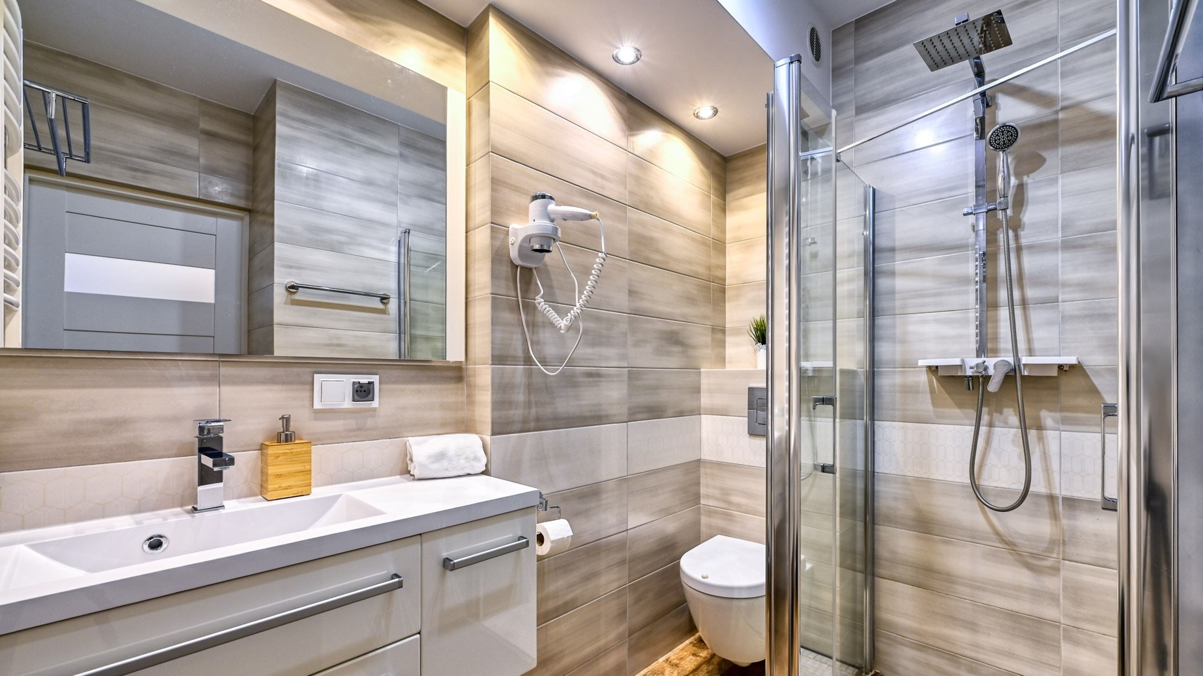 A modern bathroom with a glass shower enclosure, a vanity with a sink, and a toilet.
