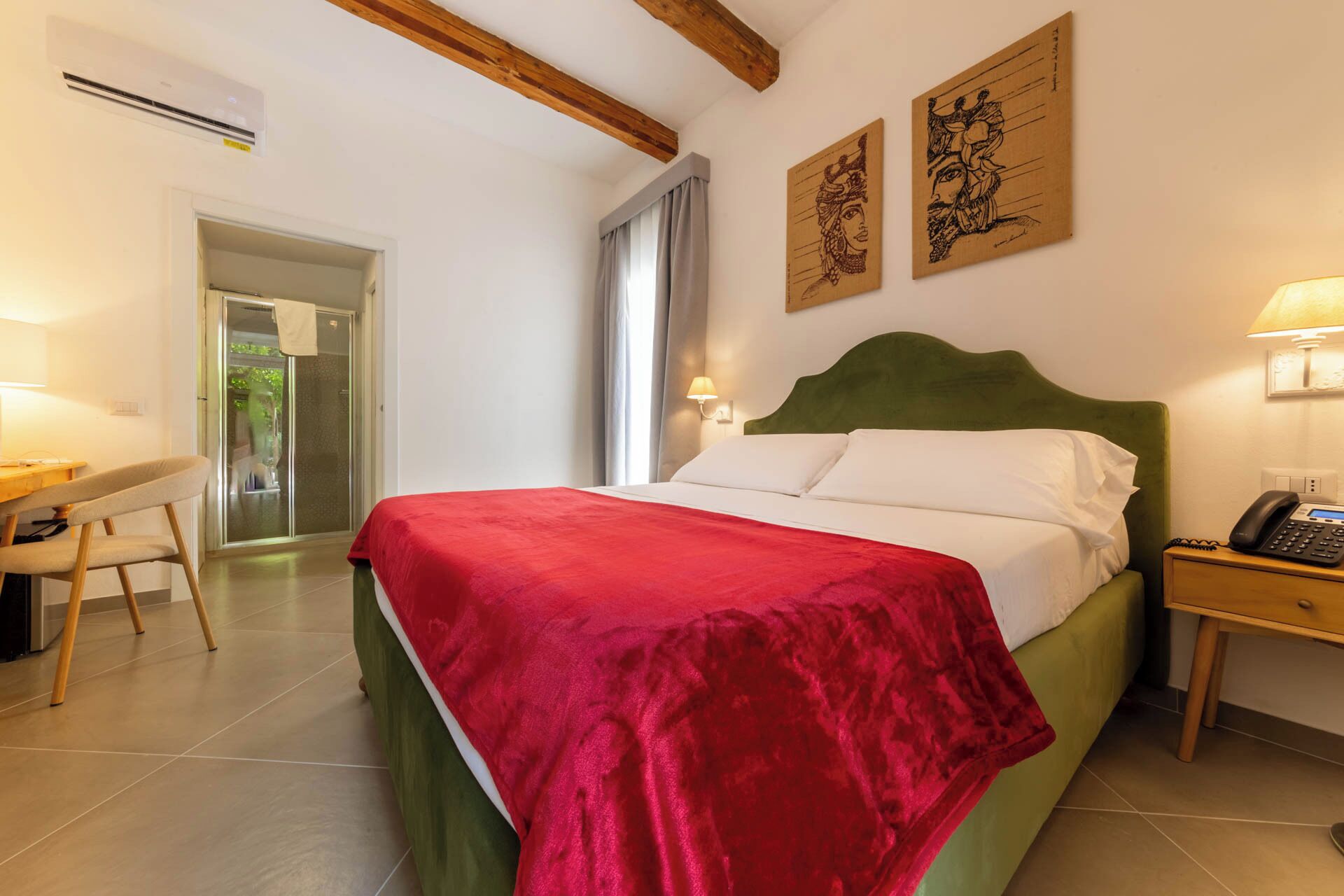 Hotelkamer met een bed, bureau, stoel, nachtkastje en een telefoon aan de muur.